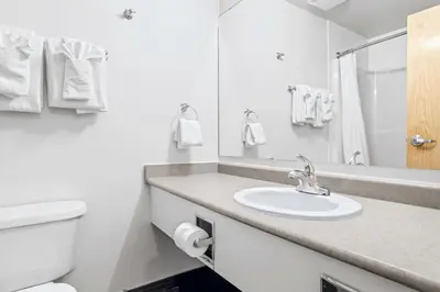 a white bathroom with a sink and a toilet at Canmore Getaway 2 Beds plus Savings in Canmore
