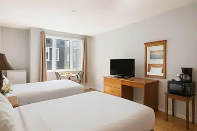a hotel room with two beds and a television at Canmore Getaway 2 Beds plus Savings in Canmore