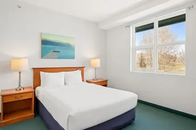 a white bedroom with a bed and two windows at Serene 1BR Retreat with Mountain Views in Canmore