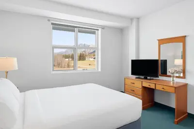 a bedroom with a bed and a desk with a television at Serene 1BR Retreat with Mountain Views in Canmore