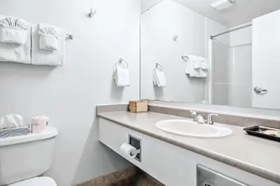 a white bathroom with a sink and a toilet at Serene 1BR Retreat with Mountain Views in Canmore