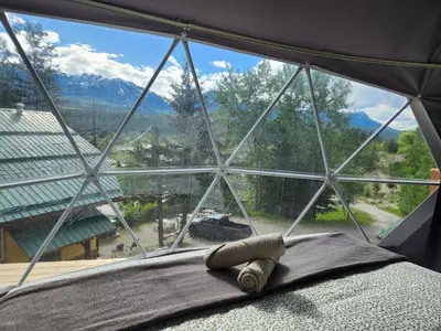 a bed in a room with a large window at Alpenrose Dome Hottubs Mountains view sleep 4 in Golden