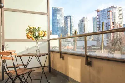 a table and chairs on a balcony with a view of a city at Beautiful Downtown Unit in Vancouver