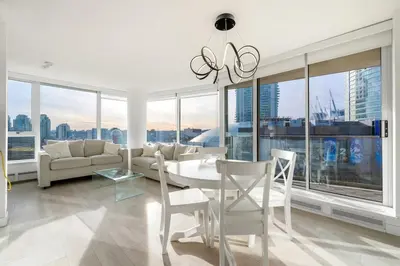 a living room with a table and chairs and windows at Bright 3BR Downtown Vancouver Condo w Pool & Gym in Vancouver