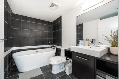 a bathroom with a tub and a toilet and a sink at Bright 3BR Downtown Vancouver Condo w Pool & Gym in Vancouver