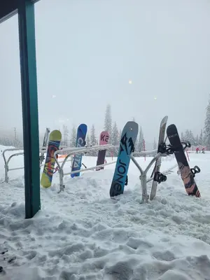 a row of snowboards on a bench in the snow at Creekside Oasis on Mara in Sicamous