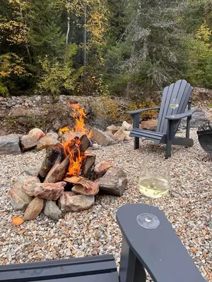 a fire pit with a bench and a glass of wine at Creekside Oasis on Mara in Sicamous