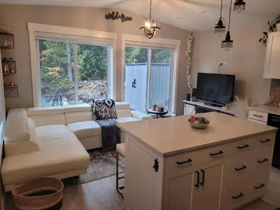 a kitchen and living room with a couch and a table at Creekside Oasis on Mara in Sicamous