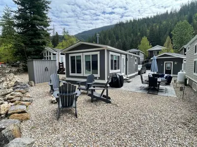 a small cabin with chairs and a table and chairs at Creekside Oasis on Mara in Sicamous