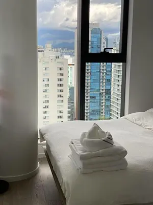 a bedroom with white towels on a bed with a window at Brand New Luxury 1 bedroom Condo in Downtown Vancouver in Vancouver
