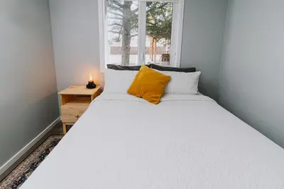 a bedroom with a large white bed with a yellow pillow at Abraham - Peaceful cabin in historic Nordegg in Nordegg