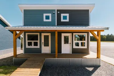 a blue house with a front porch and white doors at Adventure Knap Shack in Nordegg