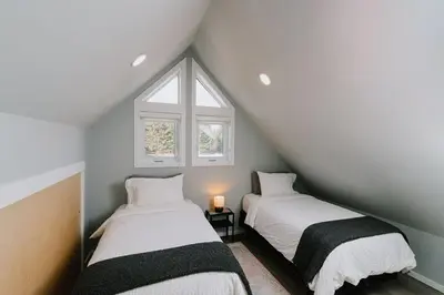 two beds in a attic room with a window at Eagle - Cozy tiny home with mountain views in Nordegg