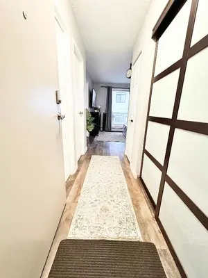 a hallway with a door and a rug at Stylish Downtown Condo near Rogers Place l Parking, Gym, Balcony & Kitchen in Edmonton