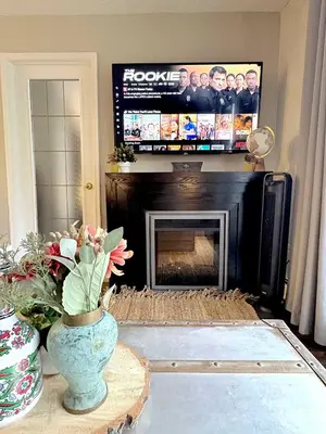 a living room with a fireplace with a tv above it at Stylish Downtown Condo near Rogers Place l Parking, Gym, Balcony & Kitchen in Edmonton