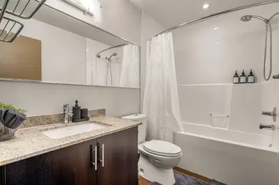 a bathroom with a toilet and a sink and a tub at The Prime Downtown | Luxe Condo + Free Parking in Calgary