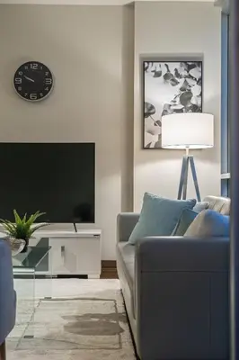 a living room with a couch and a clock on the wall at The Prime Downtown | Luxe Condo + Free Parking in Calgary