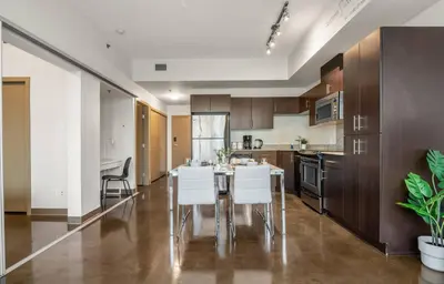 a kitchen with a table and white chairs at The Chic Downtown Residence | Luxe + Free Parking in Calgary