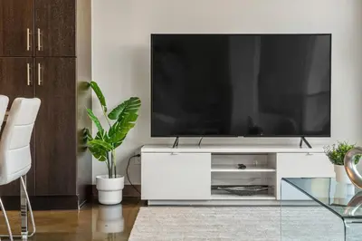 a living room with a tv on a white entertainment center at The Chic Downtown Residence | Luxe + Free Parking in Calgary