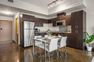 a kitchen with a table and chairs and a refrigerator at The Chic Downtown Residence | Luxe + Free Parking in Calgary
