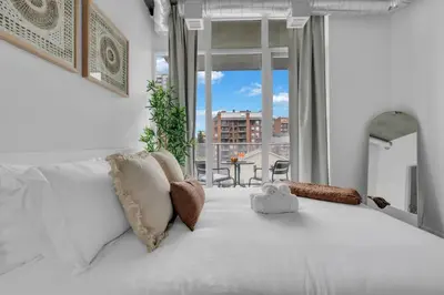 a bedroom with a white bed and a large window at Stylish Beltline 1BR w/ Parking in Calgary