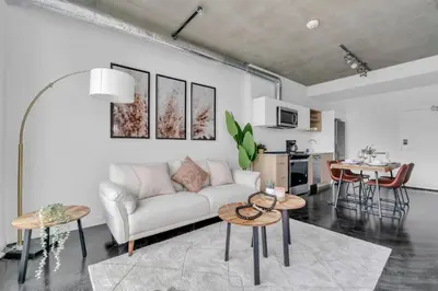 a living room with a couch and tables and a kitchen at Stylish Beltline 1BR w/ Parking in Calgary