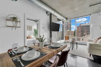 a dining room with a table and chairs and a living room at Stylish Beltline 1BR w/ Parking in Calgary