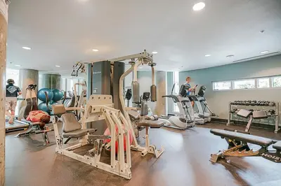 a gym with several tread machines and a man in the background at Executive Unit with Spectacular Views in Vancouver