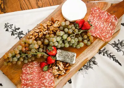 a cutting board with meat and fruit on a table at Naramata Courtyard Suites in Naramata