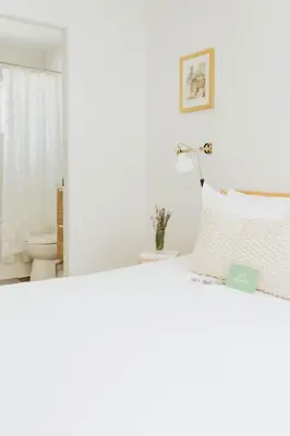 a white bedroom with a bed and a toilet at Naramata Courtyard Suites in Naramata