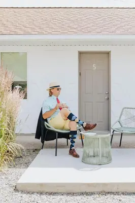 a woman sitting on a chair in front of a house at Naramata Courtyard Suites in Naramata