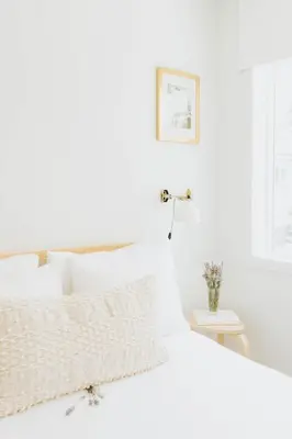 a white bedroom with a white bed and a table at Naramata Courtyard Suites in Naramata