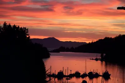 a sunset over a body of water with boats at Enchanter Ocean View Suites in Madeira Park