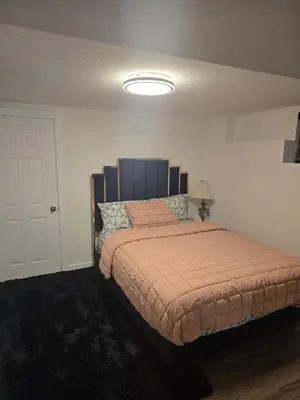 a bedroom with a bed with a orange comforter at Cozy 2-Bedroom Suite 5 Minutes Walk to Chestermere Lake in Chestermere