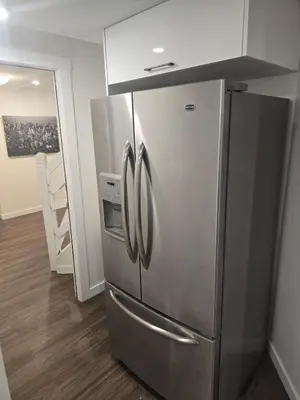 a stainless steel refrigerator in a kitchen with wooden floors at Cozy 2-Bedroom Suite 5 Minutes Walk to Chestermere Lake in Chestermere