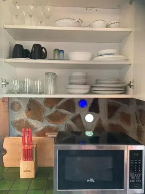 a kitchen with a microwave and plates on shelves at Entire Cordwood House 5 minutes south of town in Golden