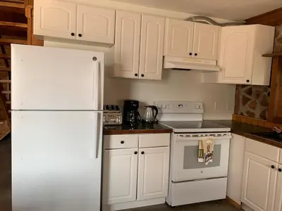 a kitchen with white cabinets and a white refrigerator at Entire Cordwood House 5 minutes south of town in Golden