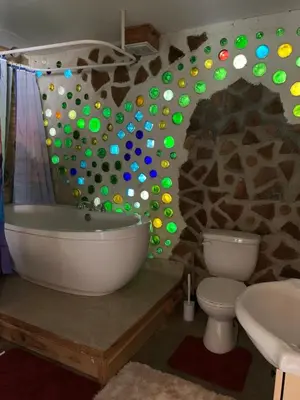 a bathroom with a tub and a toilet and a stone wall at Entire Cordwood House 5 minutes south of town in Golden