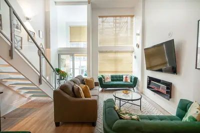 a living room with green couches and a tv at Trendy Loft in Downtown in Vancouver
