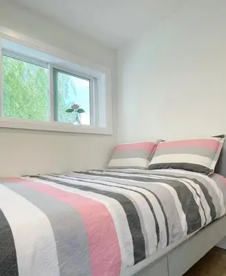 a bedroom with a bed with a striped blanket at A Beautiful, cozy second floor room for staying in Vancouver