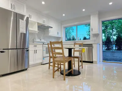 a kitchen with a table and chairs and a refrigerator at Brand new, cozy first floor room for staying in Vancouver