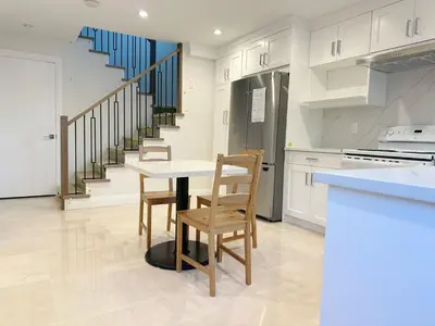 a kitchen with a table and chairs and a staircase at Brand new, cozy first floor room for staying in Vancouver