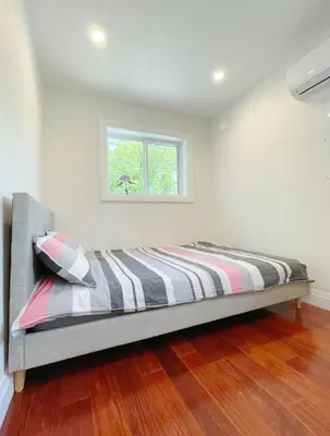 a bed in a white room with a window at Brand new, cozy first floor room for staying in Vancouver