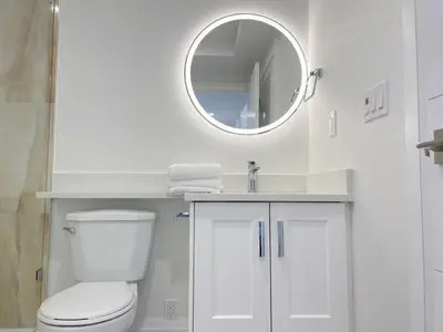 a white bathroom with a toilet and a mirror at Brand new, cozy first floor room for staying in Vancouver
