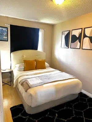 a bedroom with a large bed with two orange pillows at The house Londonderry mall in Edmonton