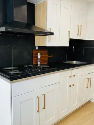 a kitchen with white cabinets and a stove top oven at The Chimney Studio with Gigantic Outdoor Fireplace in Calgary