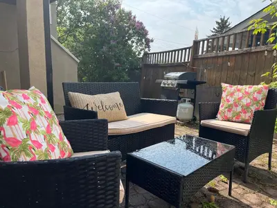 a patio with wicker chairs and tables and a grill at The Chimney Studio with Gigantic Outdoor Fireplace in Calgary