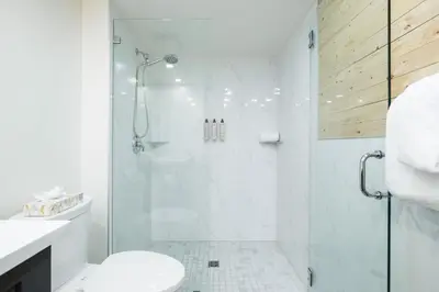 a white bathroom with a shower and a toilet at Painted Cliff by Outpost Whistler in Whistler