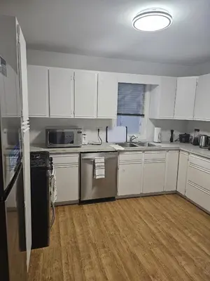 an empty kitchen with white cabinets and appliances at Aansel Suites QUEEN ROOM in Edmonton