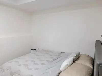 a bed in a room with a white wall at Quiet, cozy 2BR1BA private entry suite near Skytrain in Vancouver